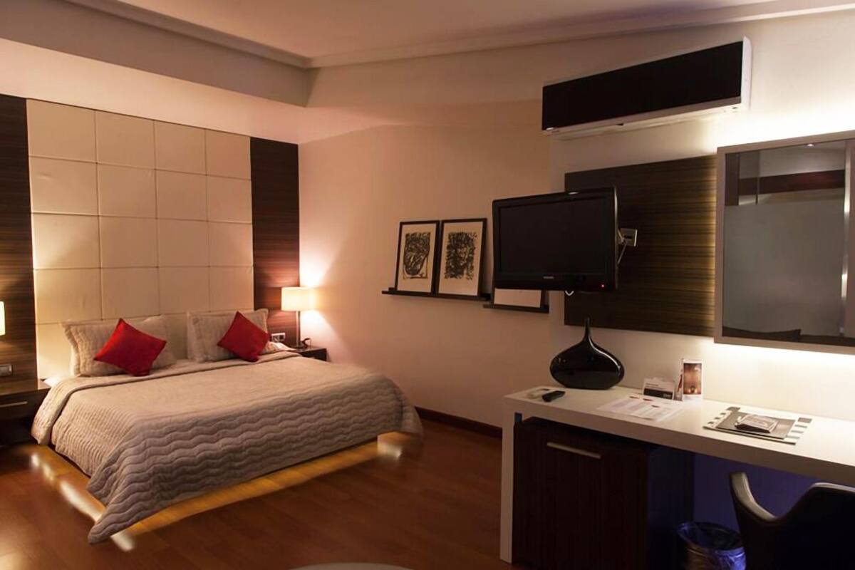 Ein Hotelzimmer mit einem Bett, einem Schreibtisch, einem Flachbildfernseher und gerahmten Bildern an der Wand.