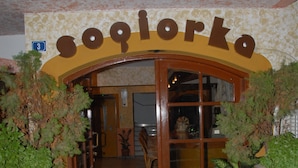 A hallway leading to a room with a sign reading "Sojorko". There are potted plants along the walls and a wooden door. - Sogiorka Apartments (Hersonissos)