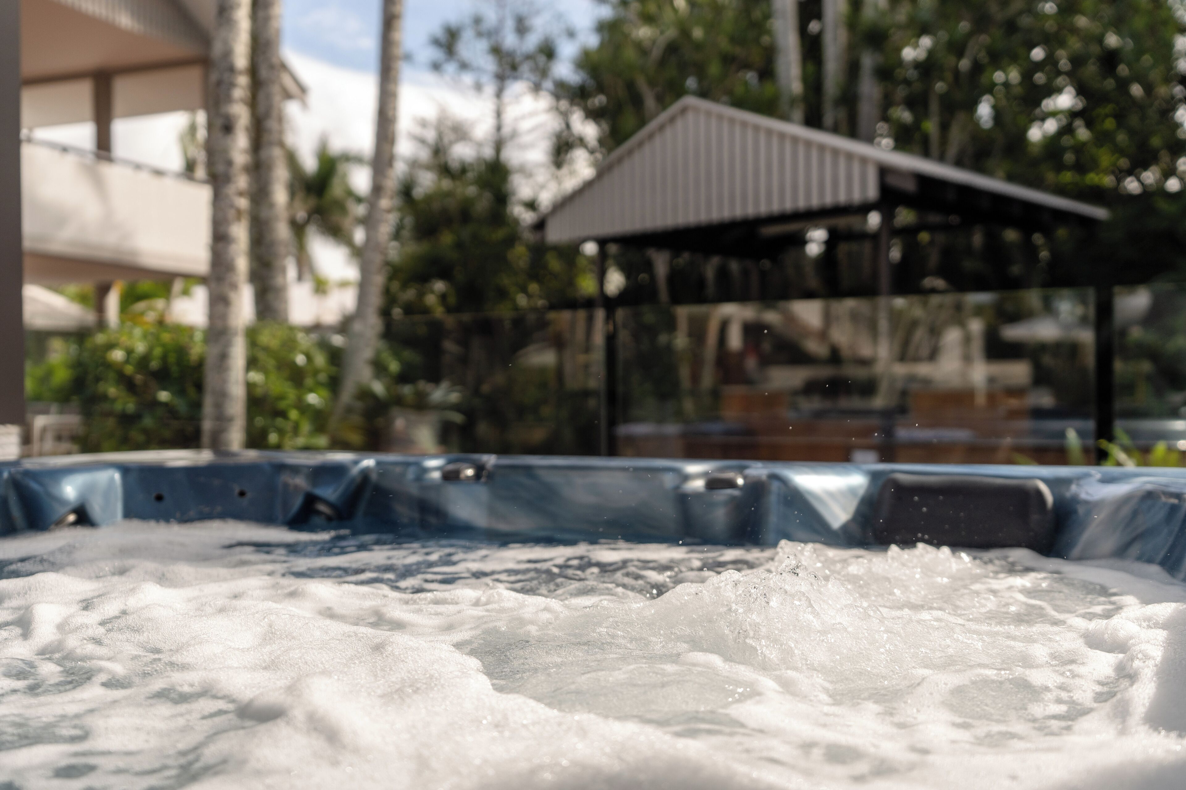 A hot tub with visible bubbles, surrounded by trees and a covered structure.