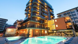 A multi-story hotel with a swimming pool, balconies, and a staircase leading to the upper floors. - Aparthotel Sheila (Jesolo)