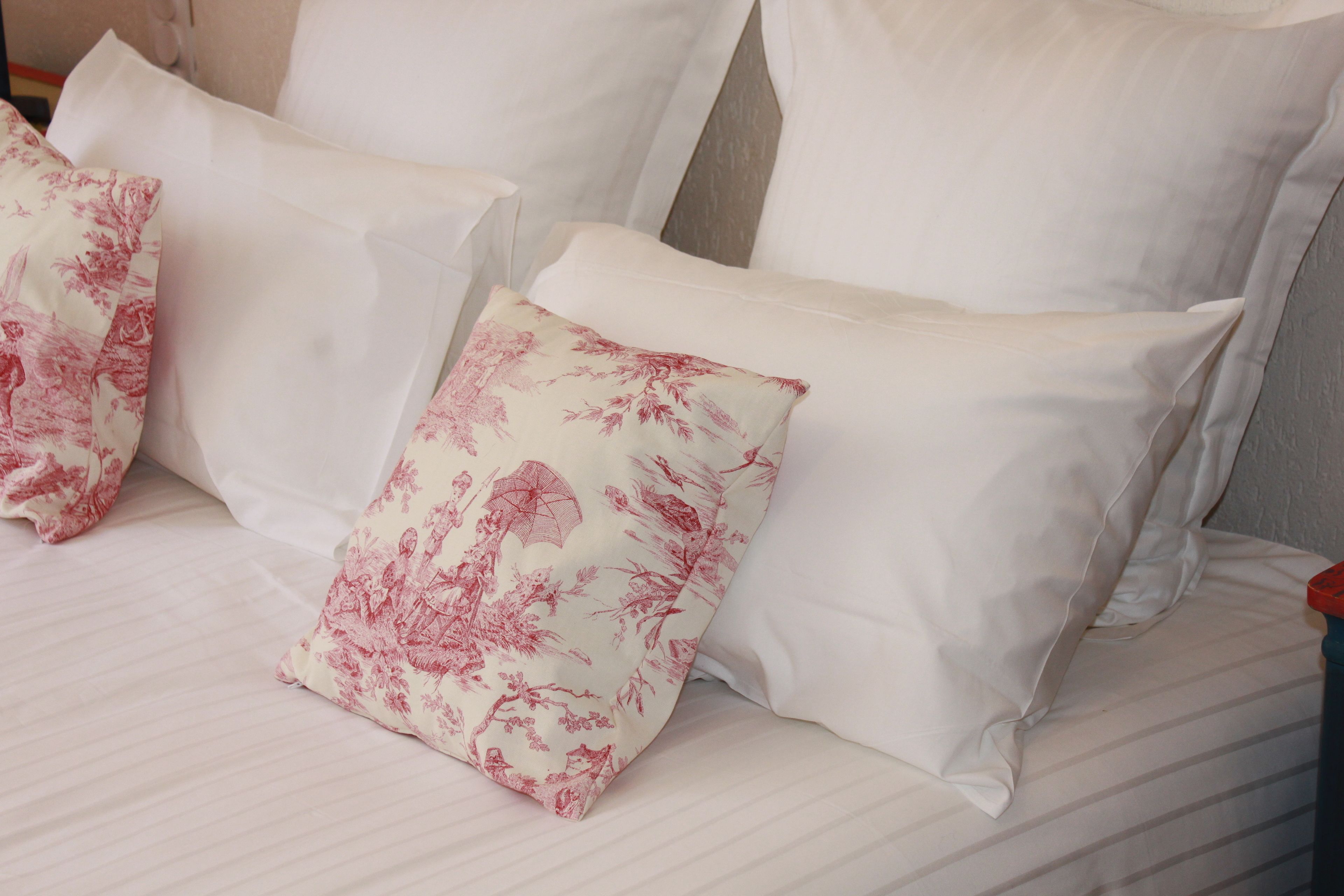 Ein Bett mit weißen Leinentüchern und Kissen mit Blumenmuster.