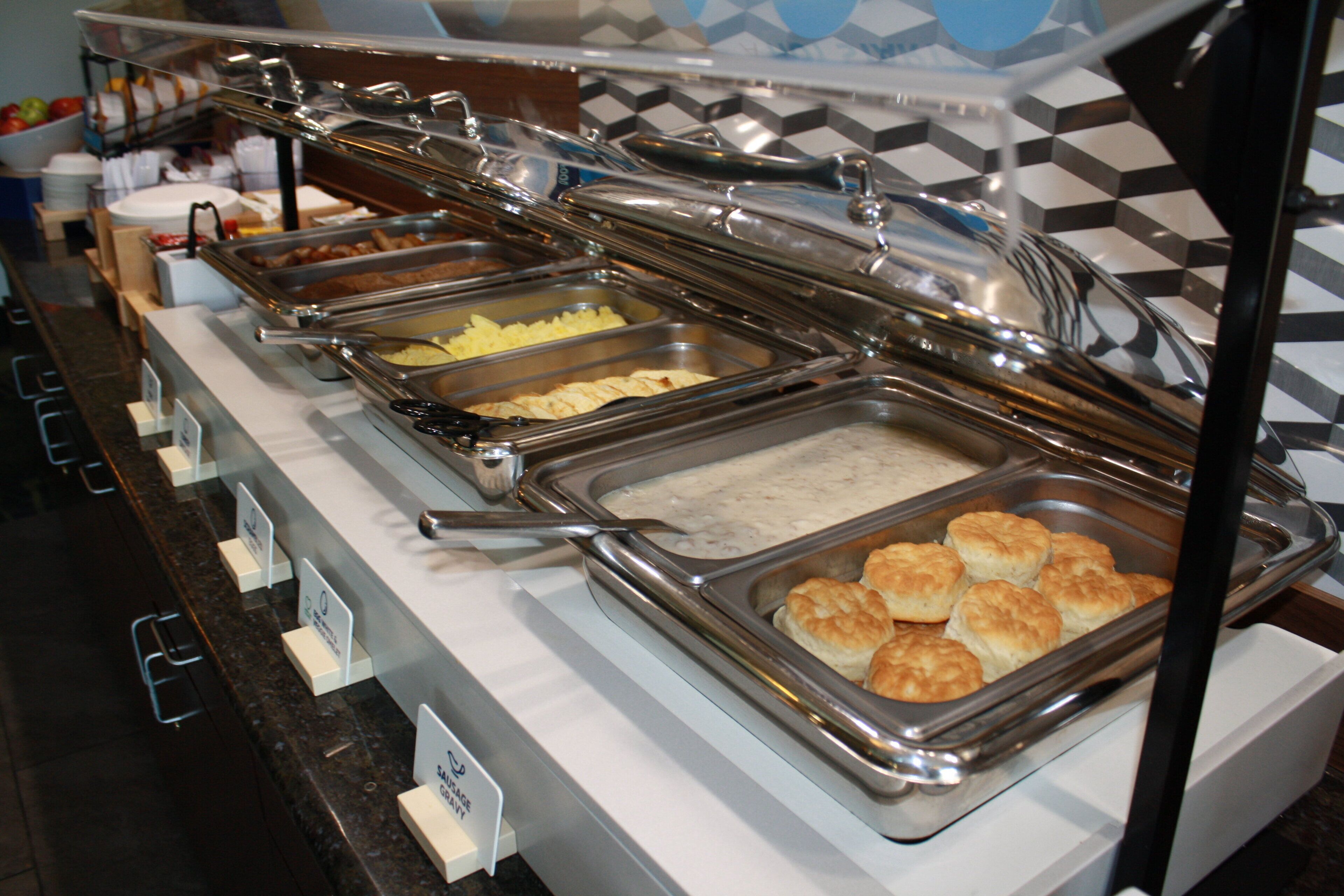 A buffet with various food items including biscuits and a variety of sauces.