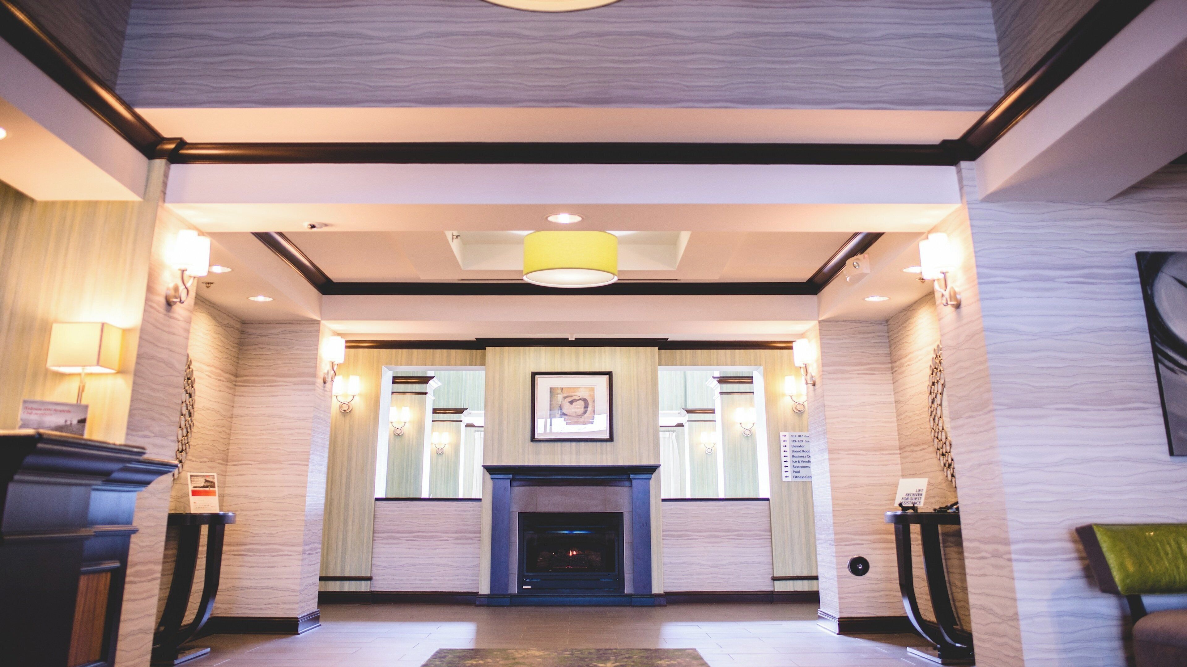 Un vestíbulo de hotel con chimenea, lámparas de pared y un mostrador de recepción.