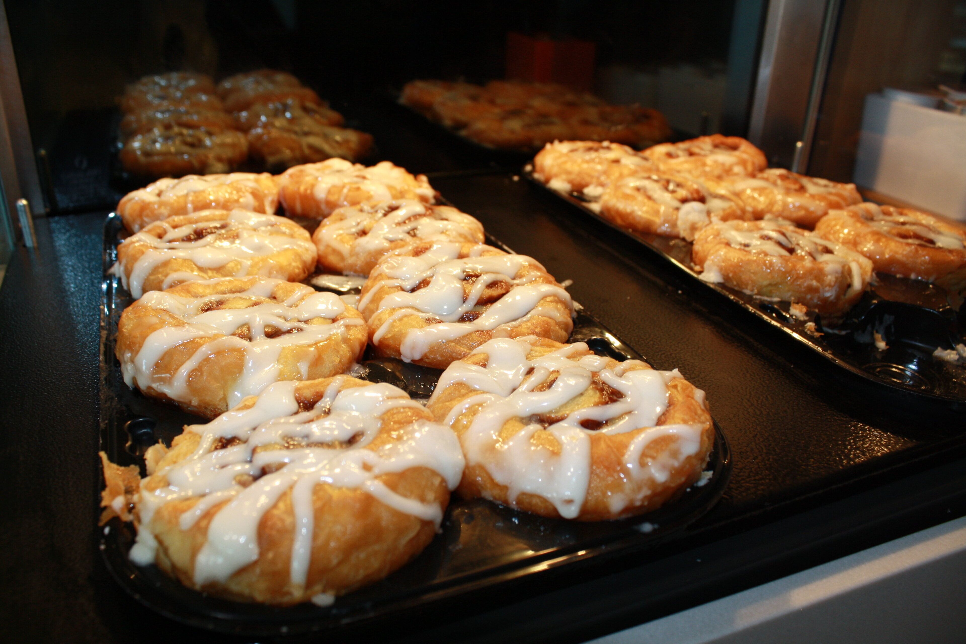 Ett urval av nybakade bakverk, troligen kanelbullar, som är upplagda på brickor.