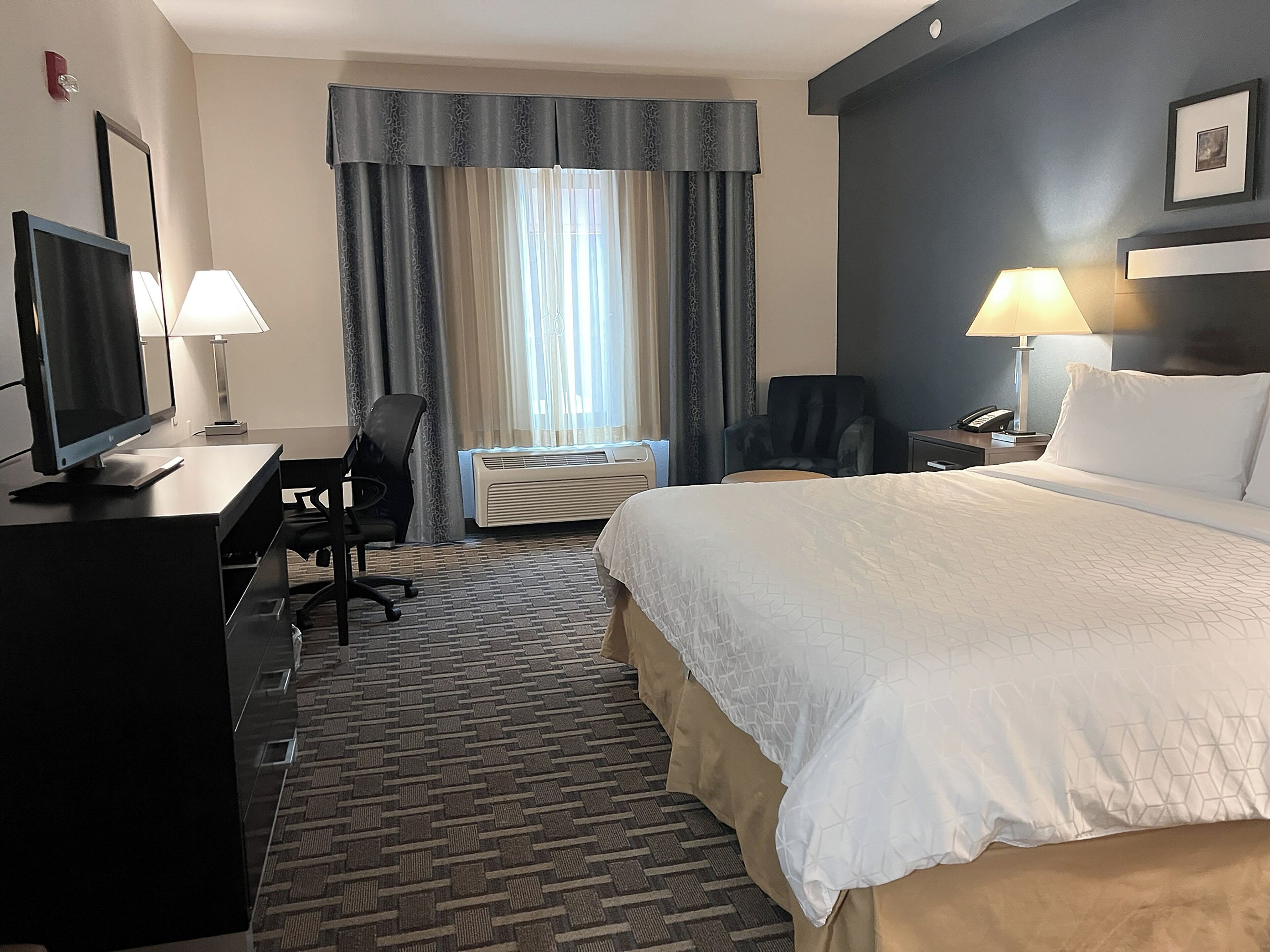 Une chambre d’hôtel équipée d’un lit, d’un bureau, d’une chaise et d’un téléviseur.