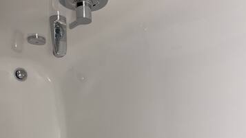 Une baignoire blanche avec un robinet chromé et un seul bouton chromé.
