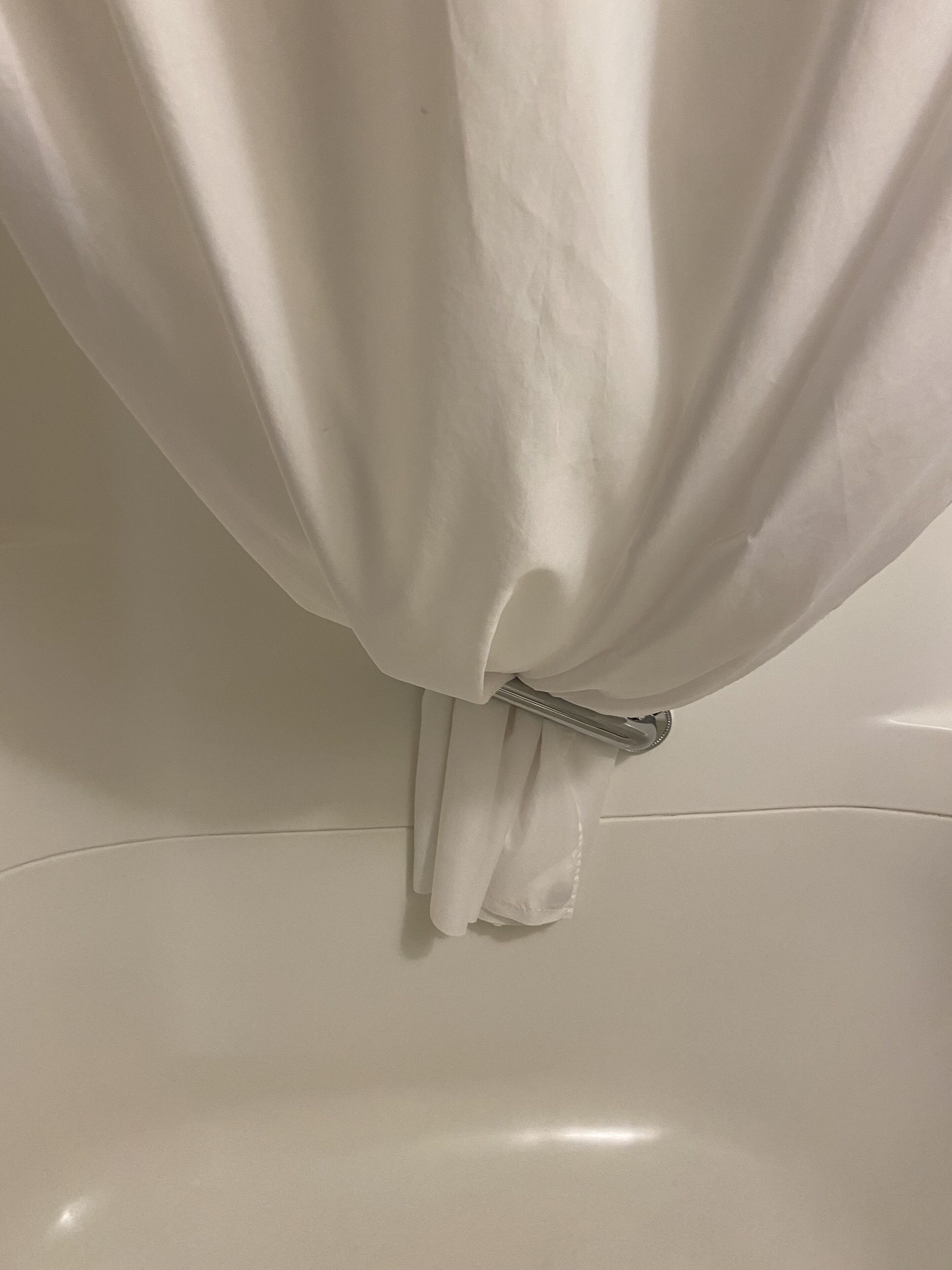 A white bathtub with a metal faucet and a white towel hanging on the side.