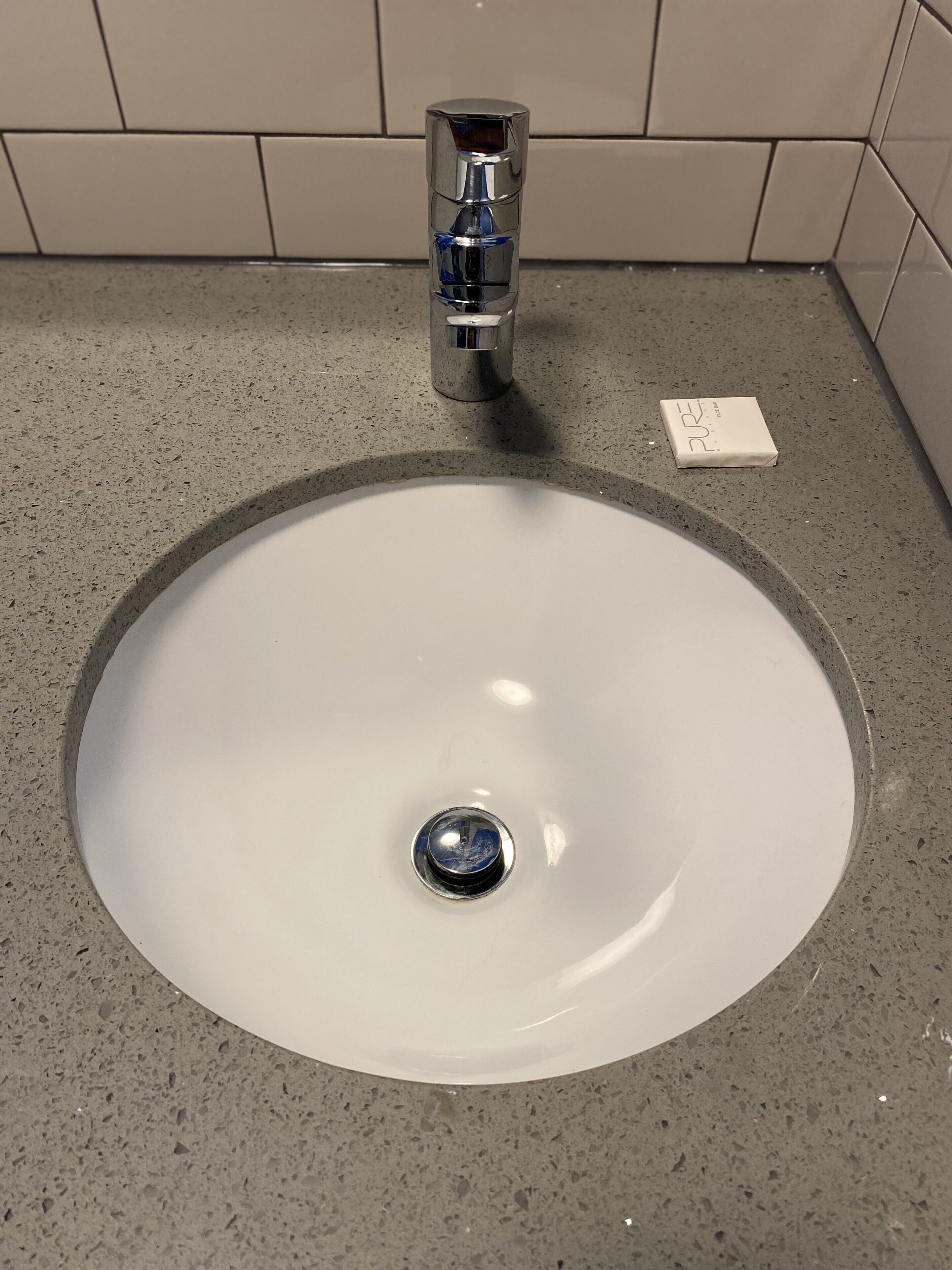 A bathroom sink with a chrome faucet and a soap dispenser on the countertop.