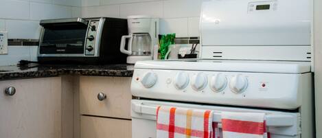 Una cocina equipada con microondas, cafetera y estufa.