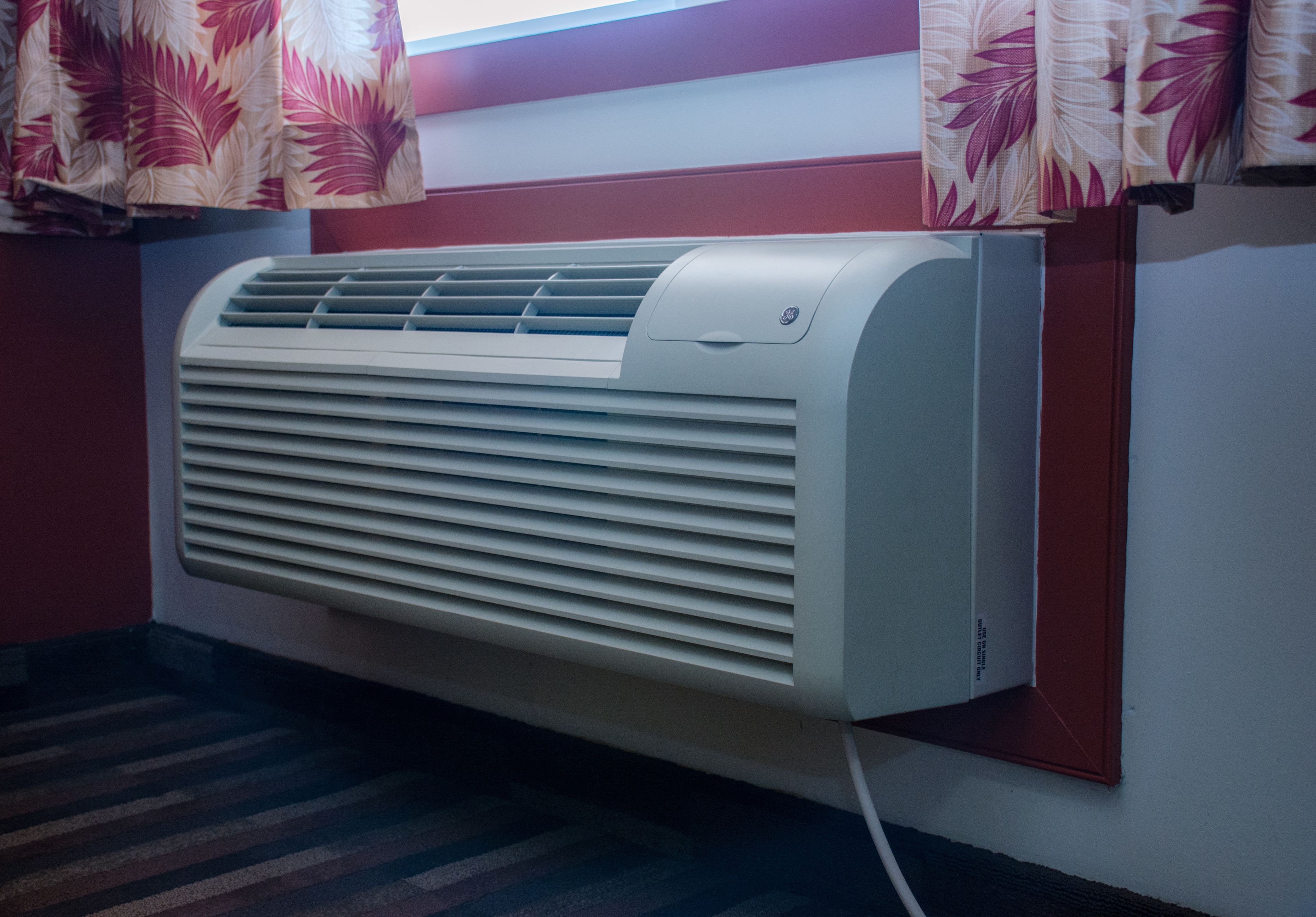 A wall-mounted air conditioner with a control panel and a power cord.