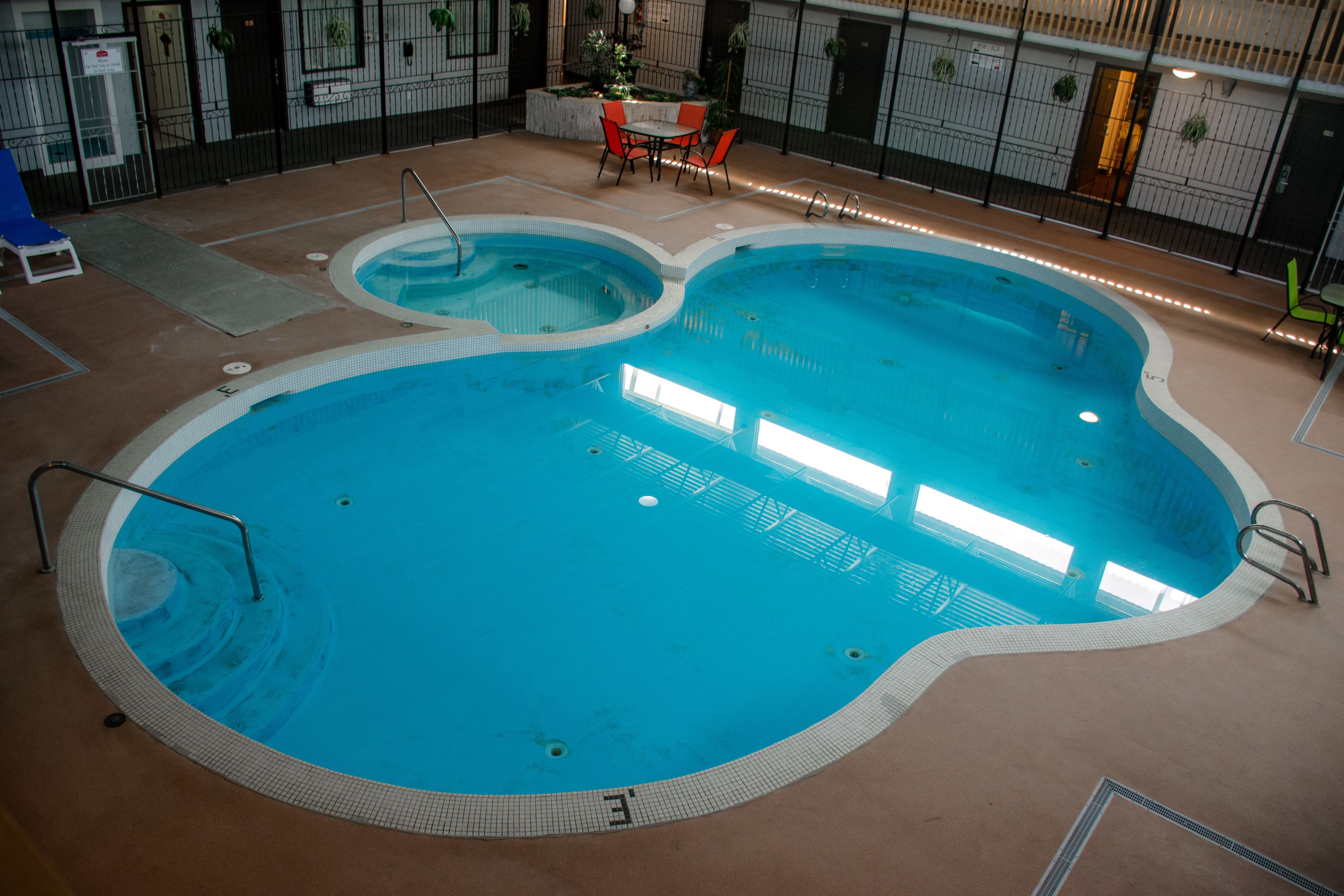 Ein Hallenbad mit mehreren Bahnen, einer Sitzgelegenheit mit Stühlen und einem kleinen Tisch.