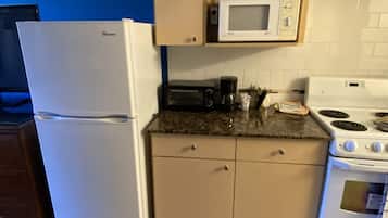 A compact kitchen with a refrigerator, microwave, toaster, coffee maker, and stove.