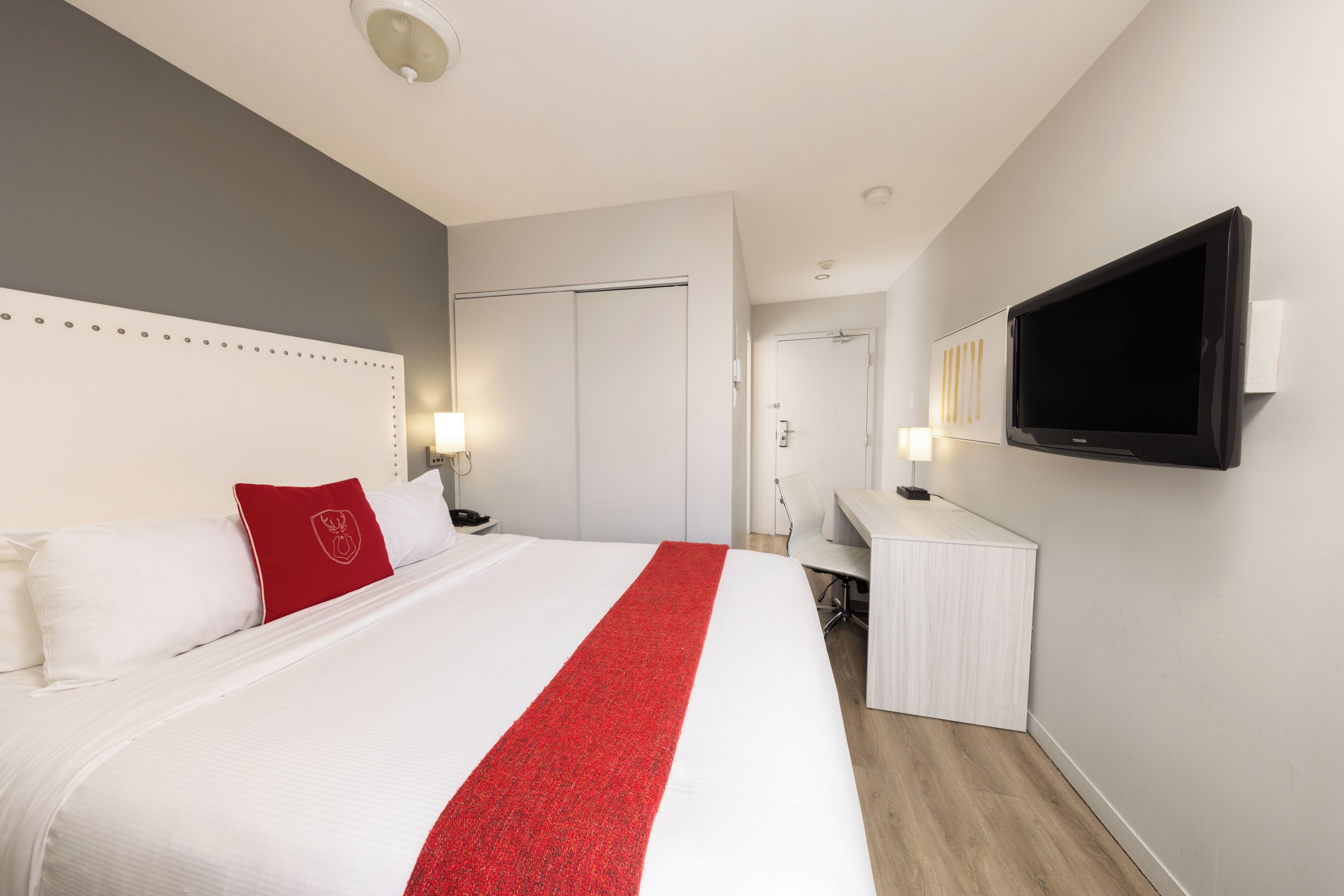 Una habitación de hotel con una cama grande, un escritorio, un televisor de pantalla plana y una puerta que da a un baño.