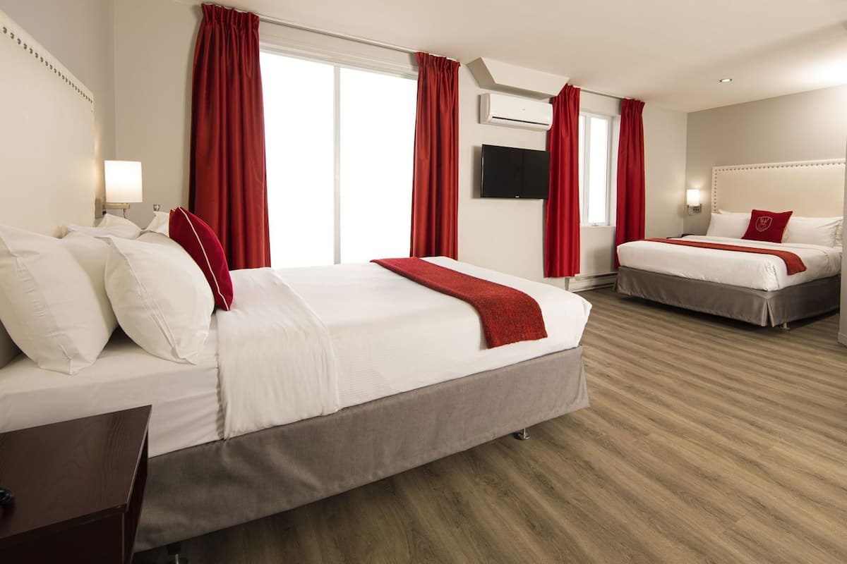 A hotel room with two beds, a TV, and a desk.