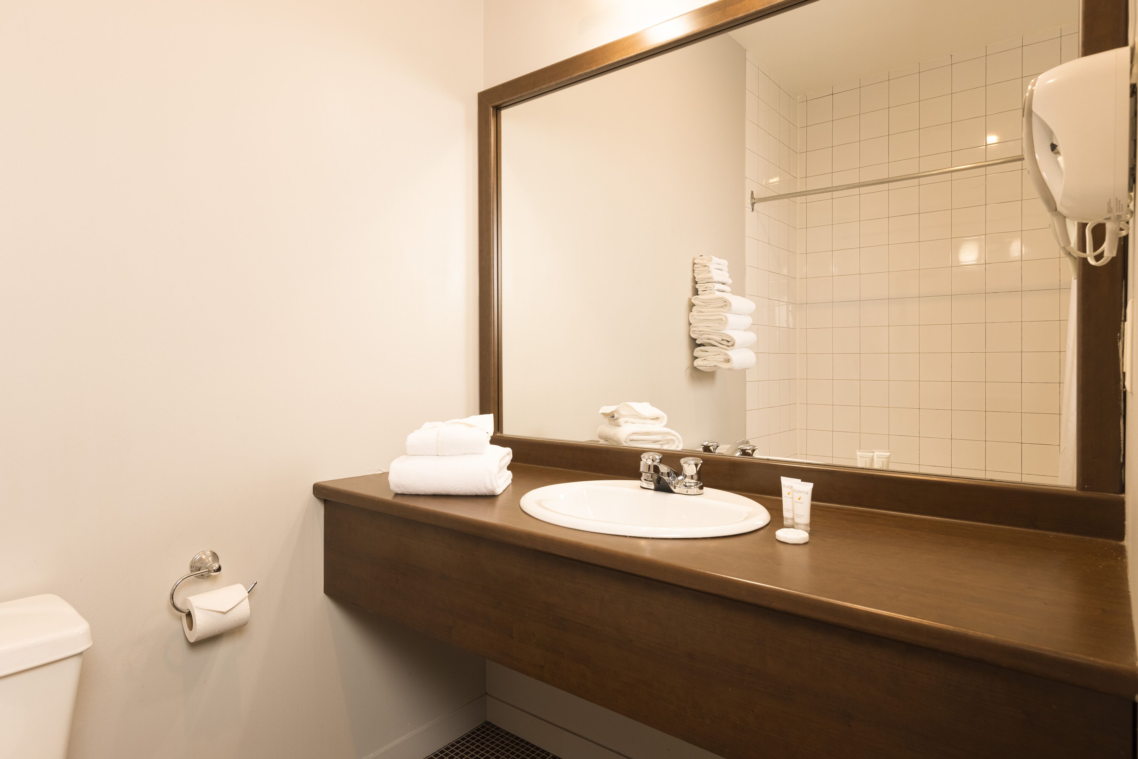 Un baño con lavamanos, espejo y perchero para toallas.
