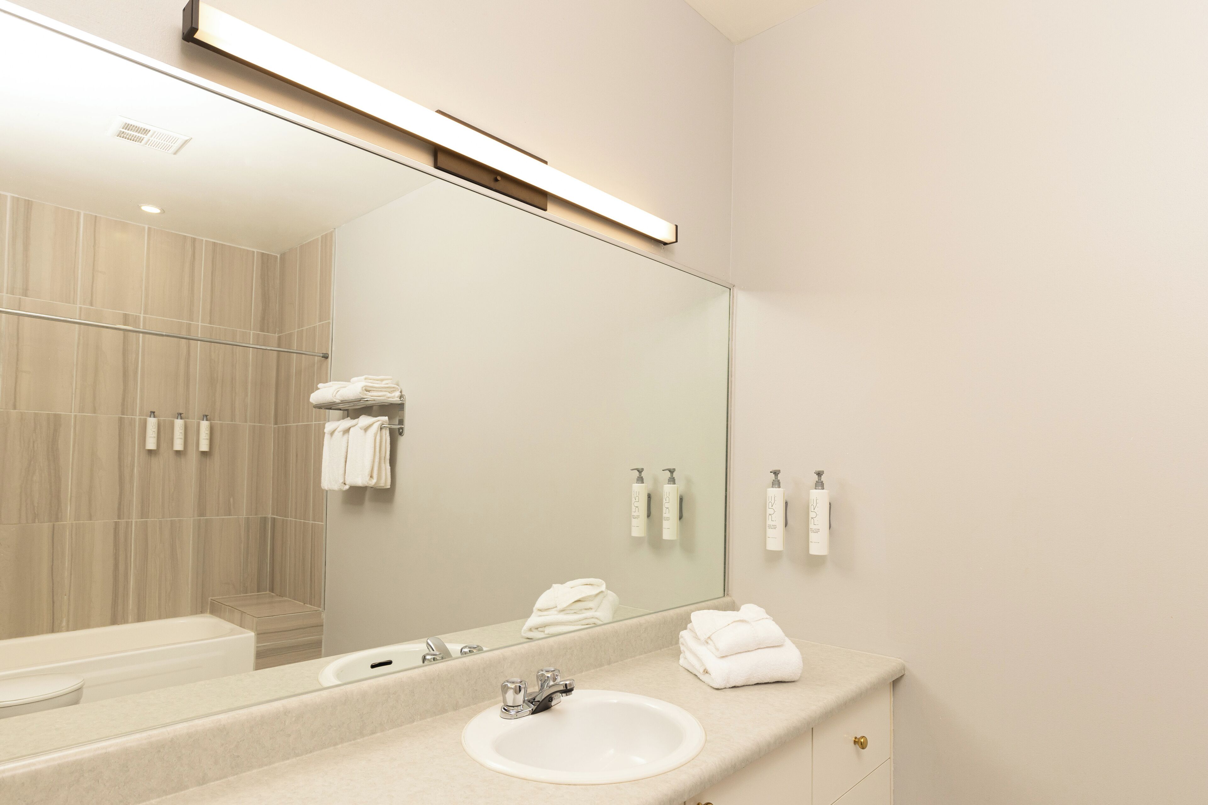 A modern bathroom with a large mirror, a sink, and a shower area.