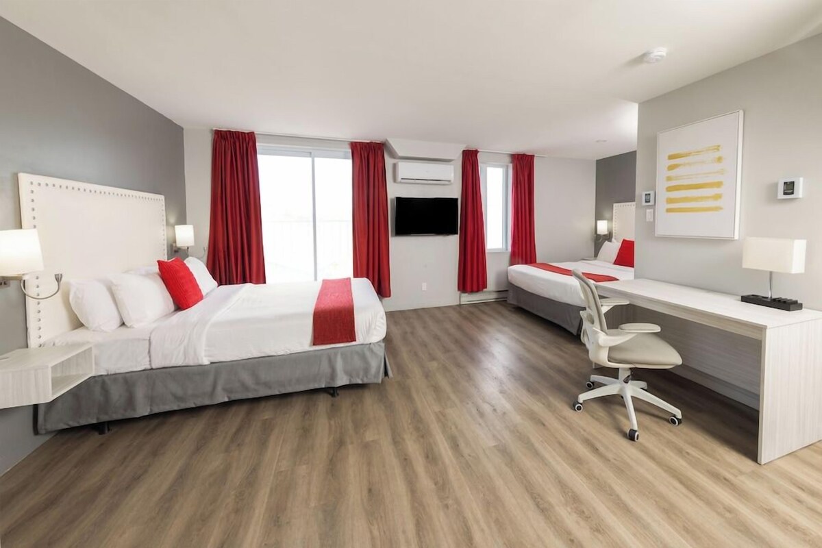 A hotel room with a bed, a desk, a chair, and a TV.
