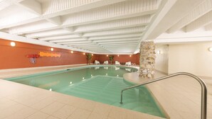 An indoor swimming pool with a stone wall, white ceiling, and a few lounge chairs. - Hôtel du Nord (Québec City)
