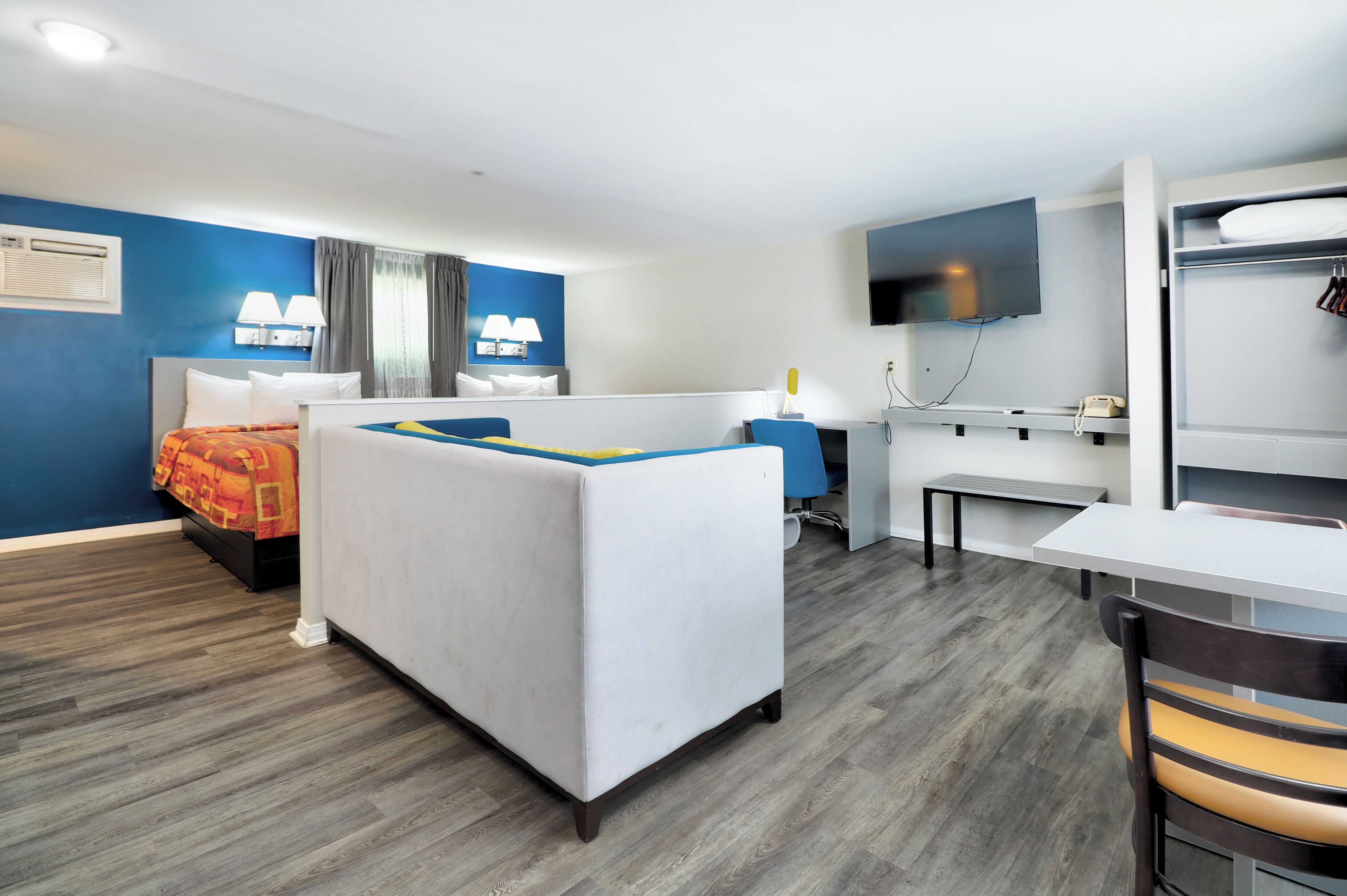 A hotel room with a bed, desk, chair, TV, and wardrobe.