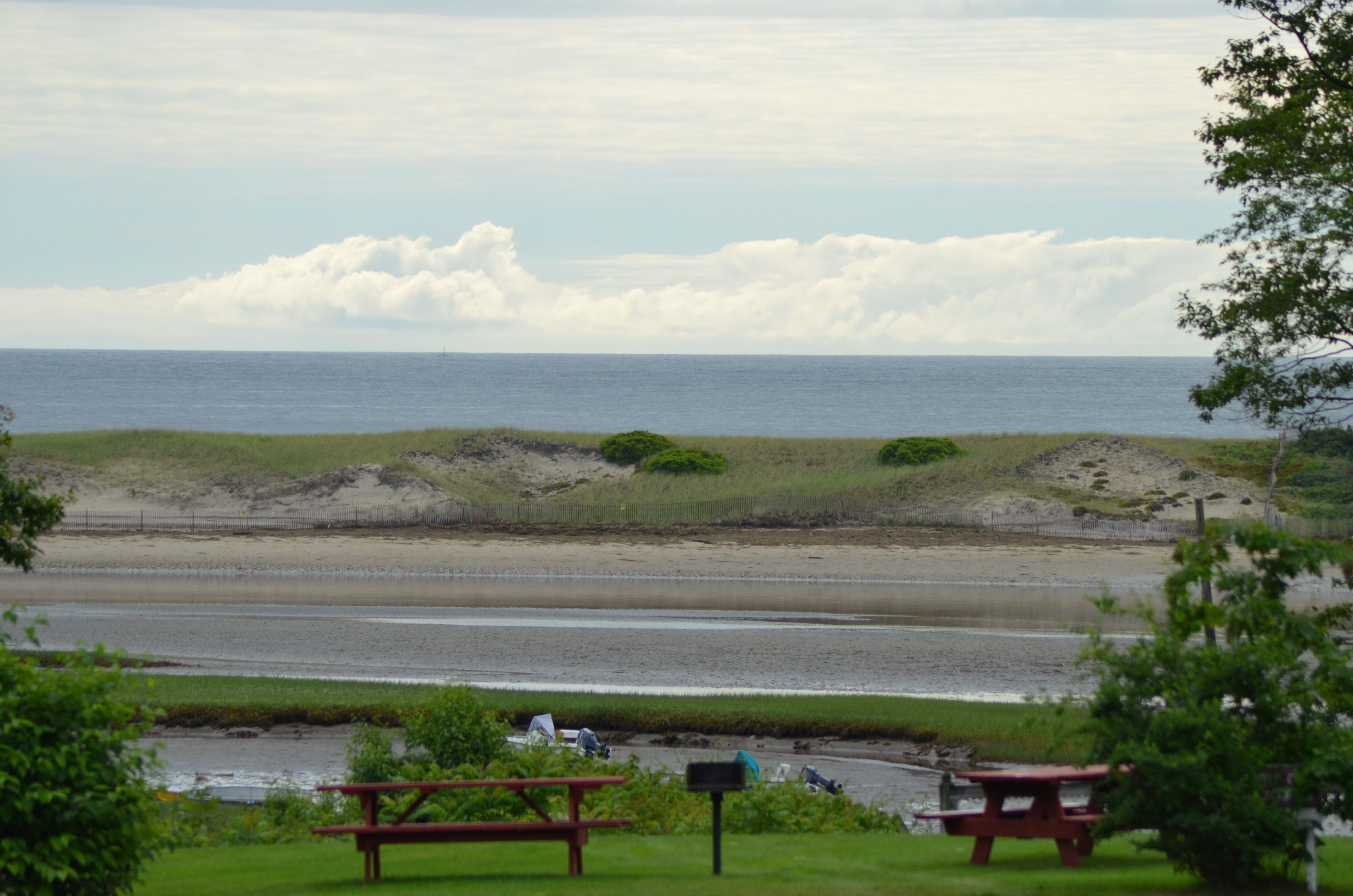 Blick auf die Küste mit Strand, Picknicktischen und einem Briefkasten.