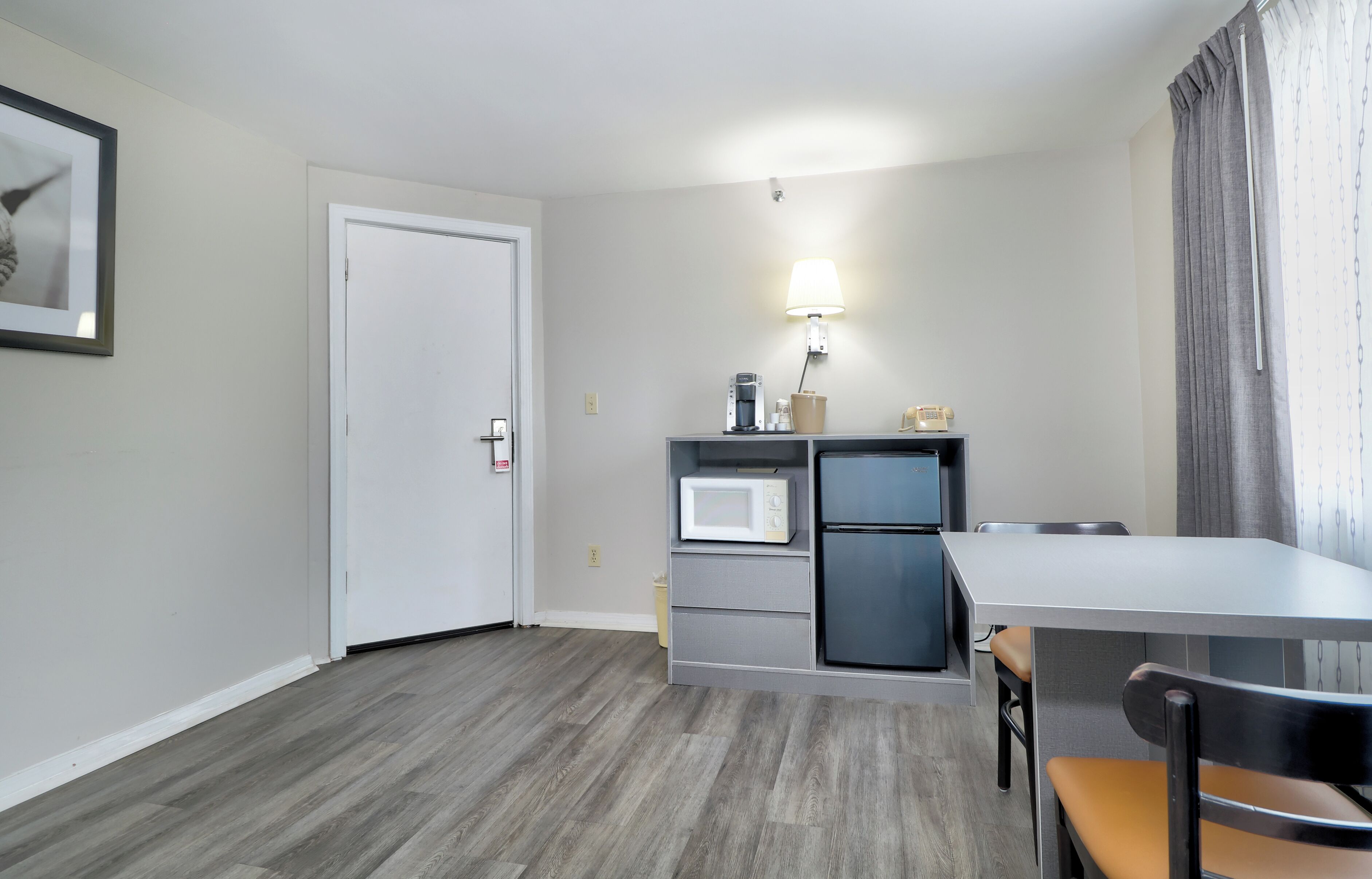 A compact kitchen with a microwave, refrigerator, and a table with a chair.