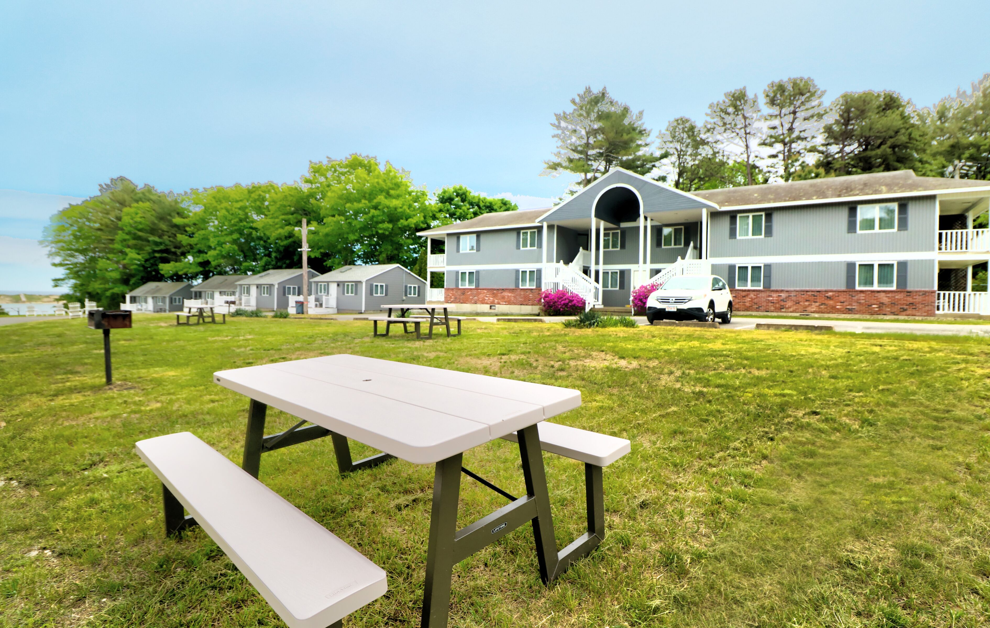 A picnic table in a grassy area with a multi-story building in the background.