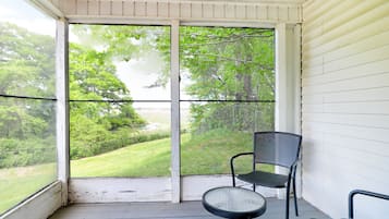 Une véranda donnant sur un paysage verdoyant, avec une chaise et une petite table.