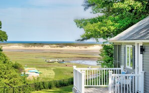 A coastal view with a grassy area, boats, and a building with a porch.
