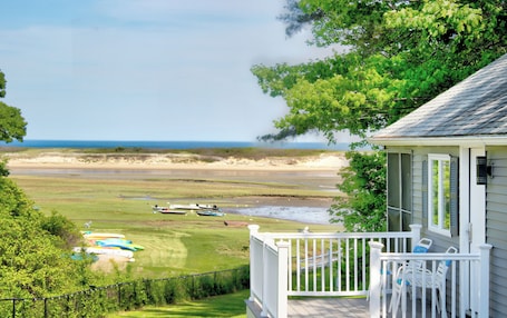 A coastal view with a grassy area, boats, and a building with a porch.