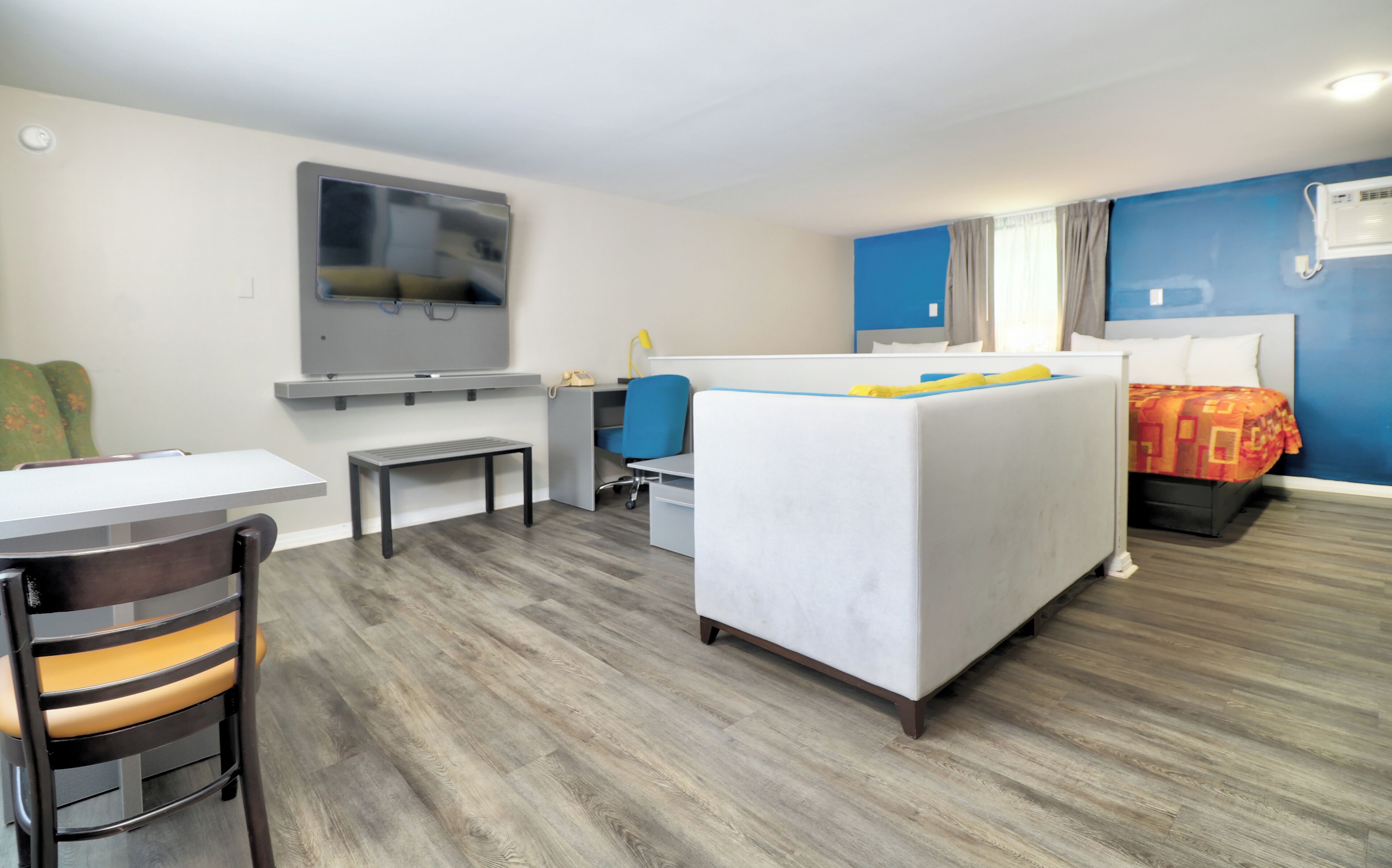 A hotel room with a bed, desk, chair, and a television on the wall.