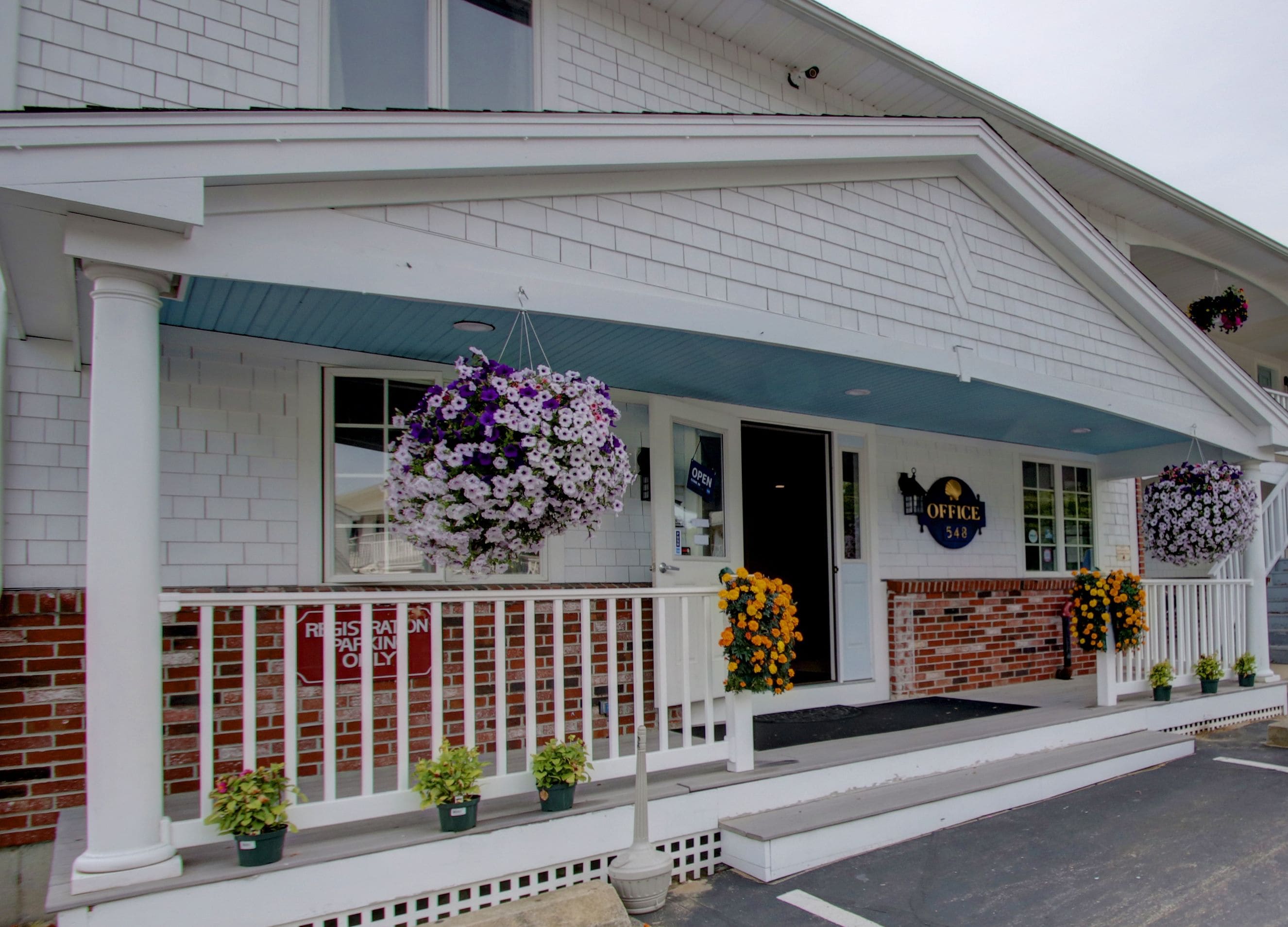 A white building with a blue awning, a brick facade, and hanging flower baskets.