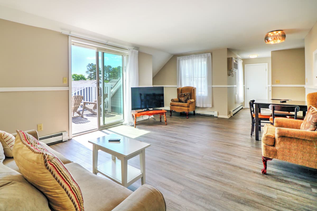 A living room with a sofa, a television, a dining table, and a chair.