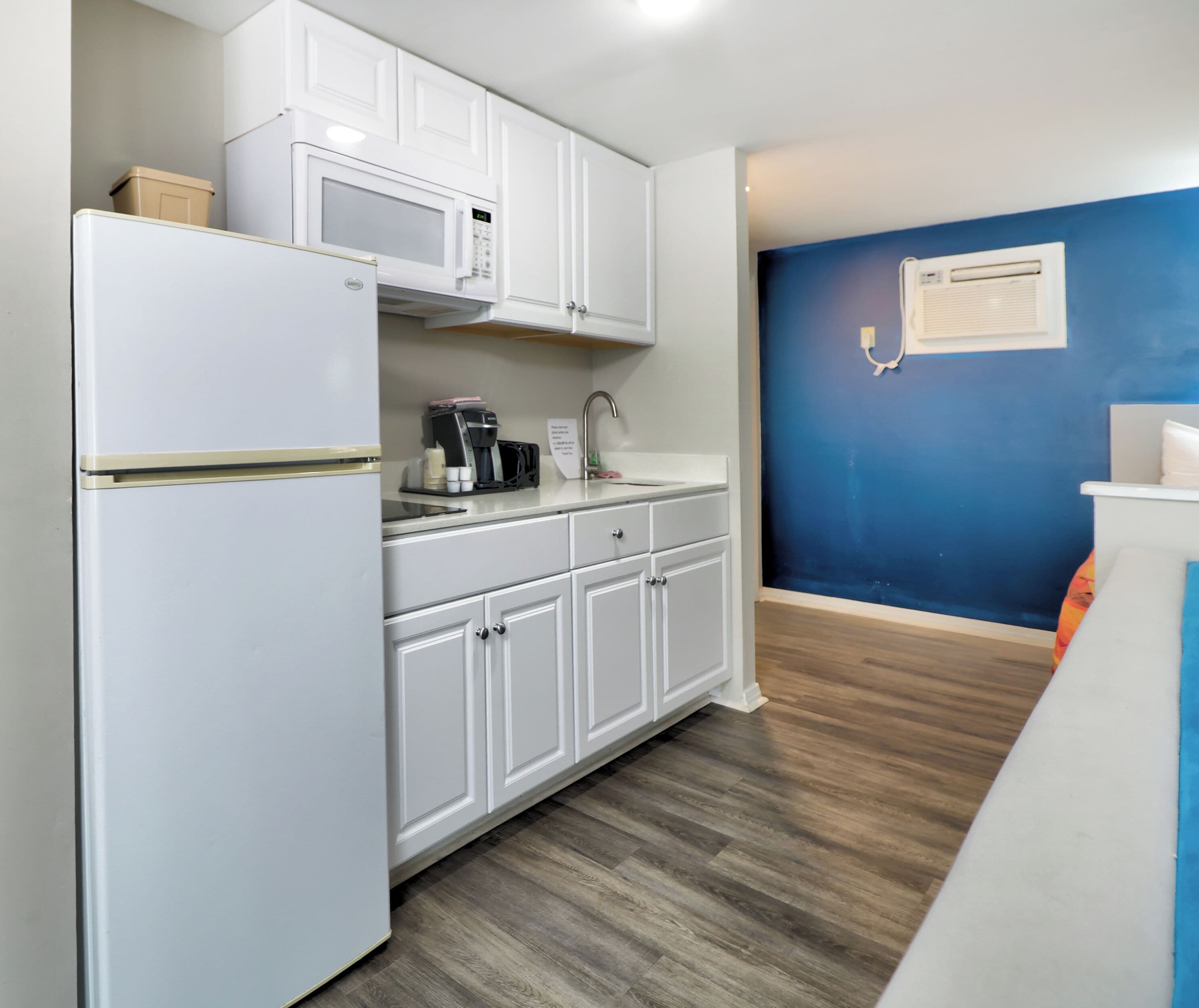 A kitchen with white cabinets, a microwave, a coffee maker, and a sink.