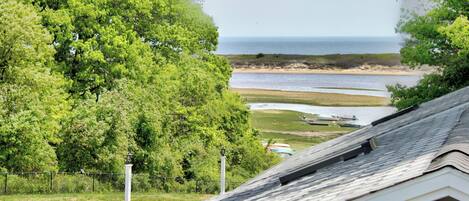 A coastal view with a grassy area, a white fence, and a lighthouse.