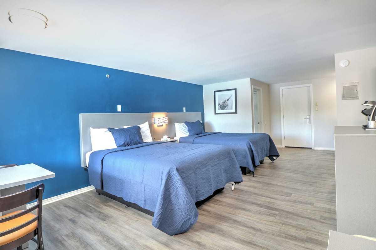 A hotel room with two beds, a desk, and a chair.