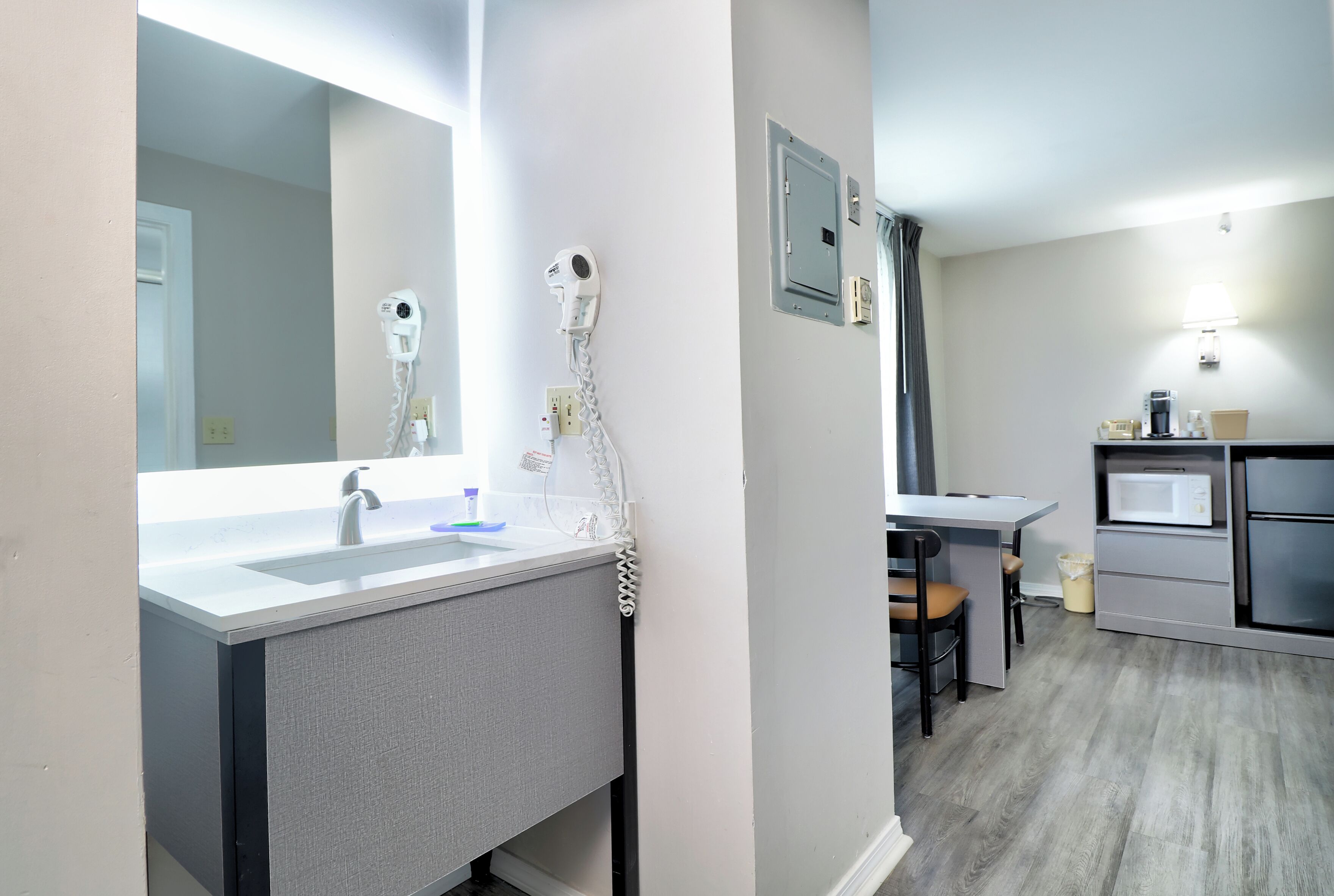 A modern bathroom with a mirror, sink, and hairdryer.