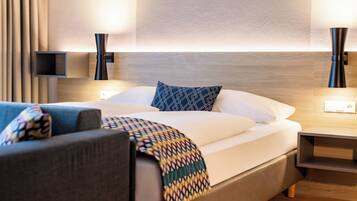 Een moderne hotelkamer met een net opgemaakt bed, een bank en een nachtkastje.