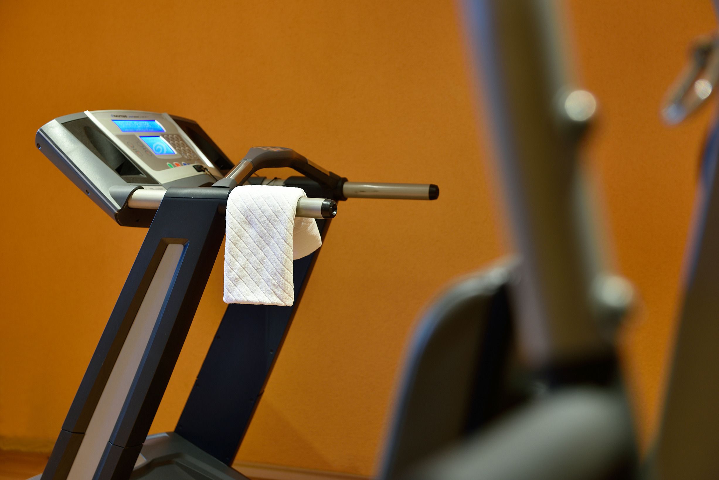 A stationary exercise bike with a digital display and a towel draped over the handlebars.