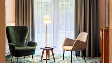 Ein Zimmer mit einem grünen Sessel, einem beigen Sessel und einer Stehlampe.
