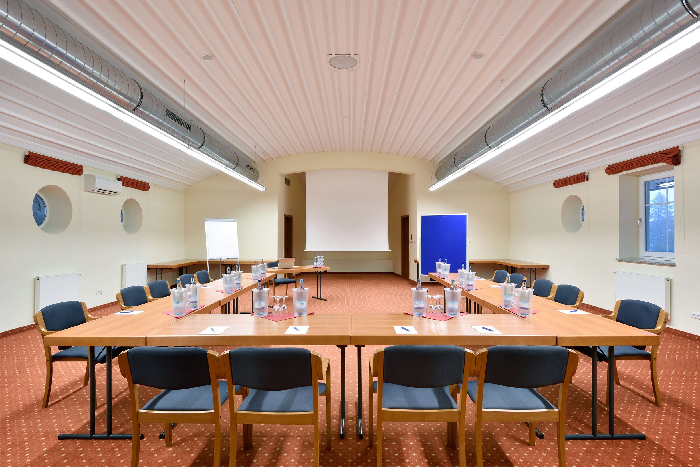 Une salle de conférence équipée d’une longue table, de chaises et d’un écran de projection.