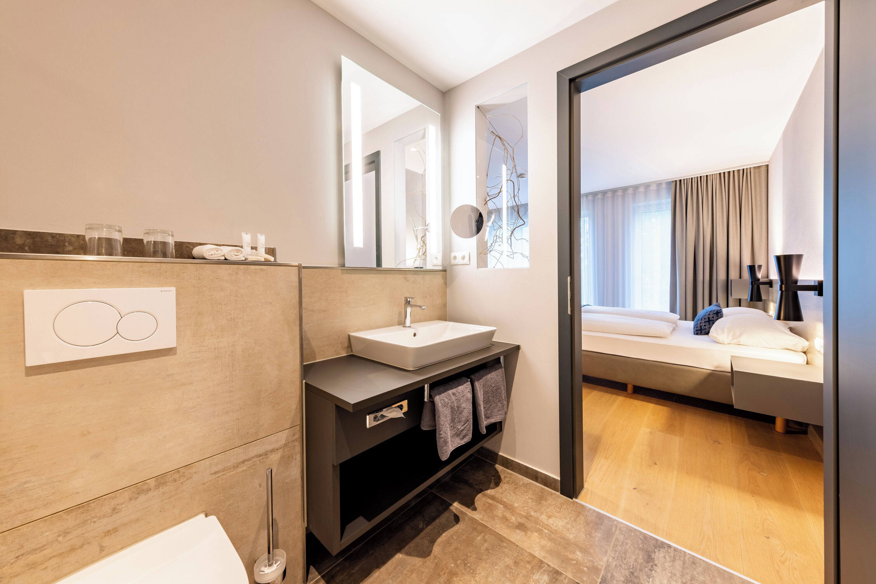Un baño moderno con lavamanos, espejo y perchero para toallas.