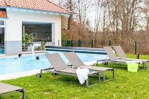 A swimming pool area with lounge chairs and a building with a tiled roof. - Parkhotel Maximilian Ottobeuren Resort&Spa (Ottobeuren)