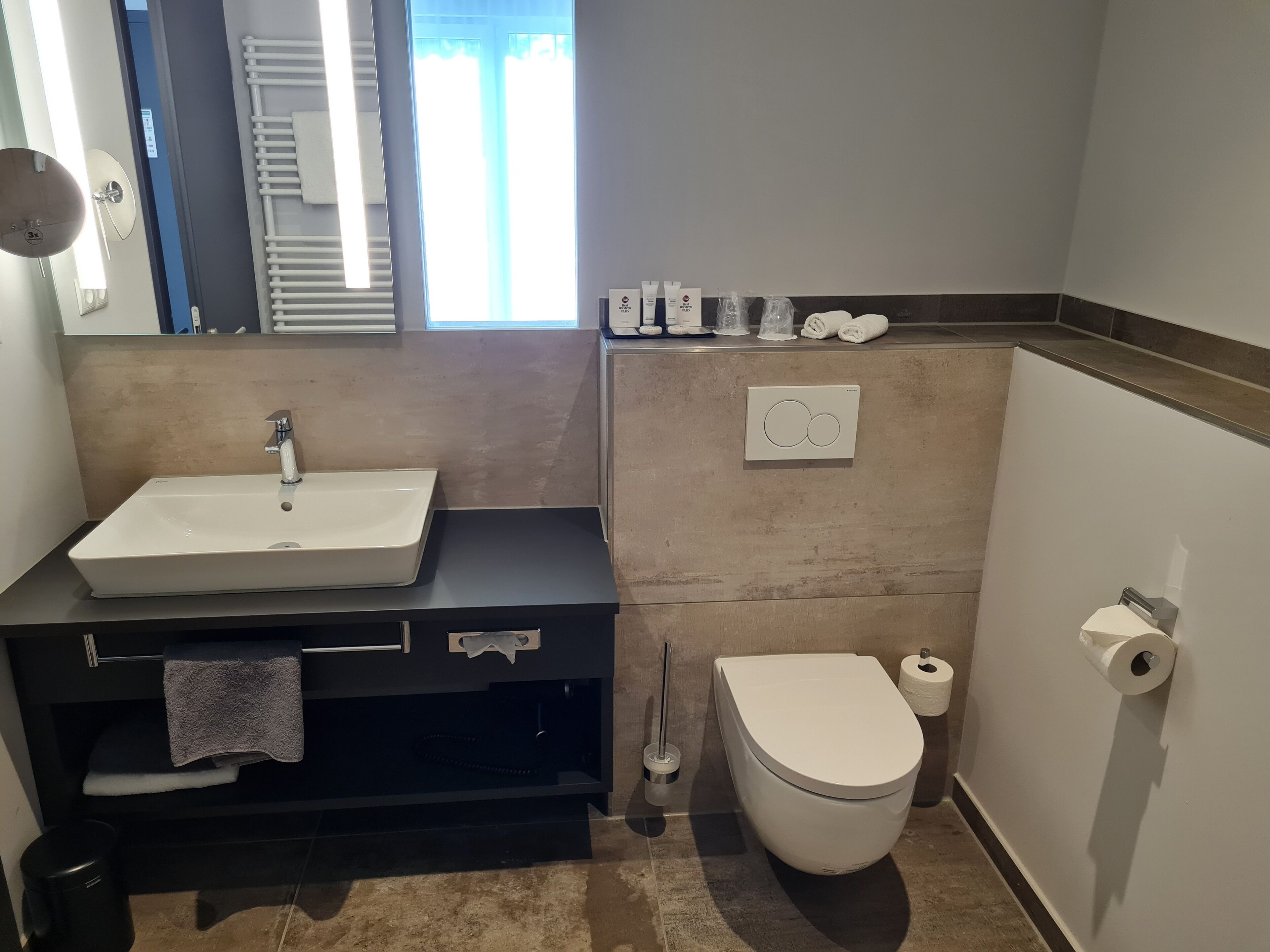 A modern bathroom with a white sink, black vanity, and a white toilet.