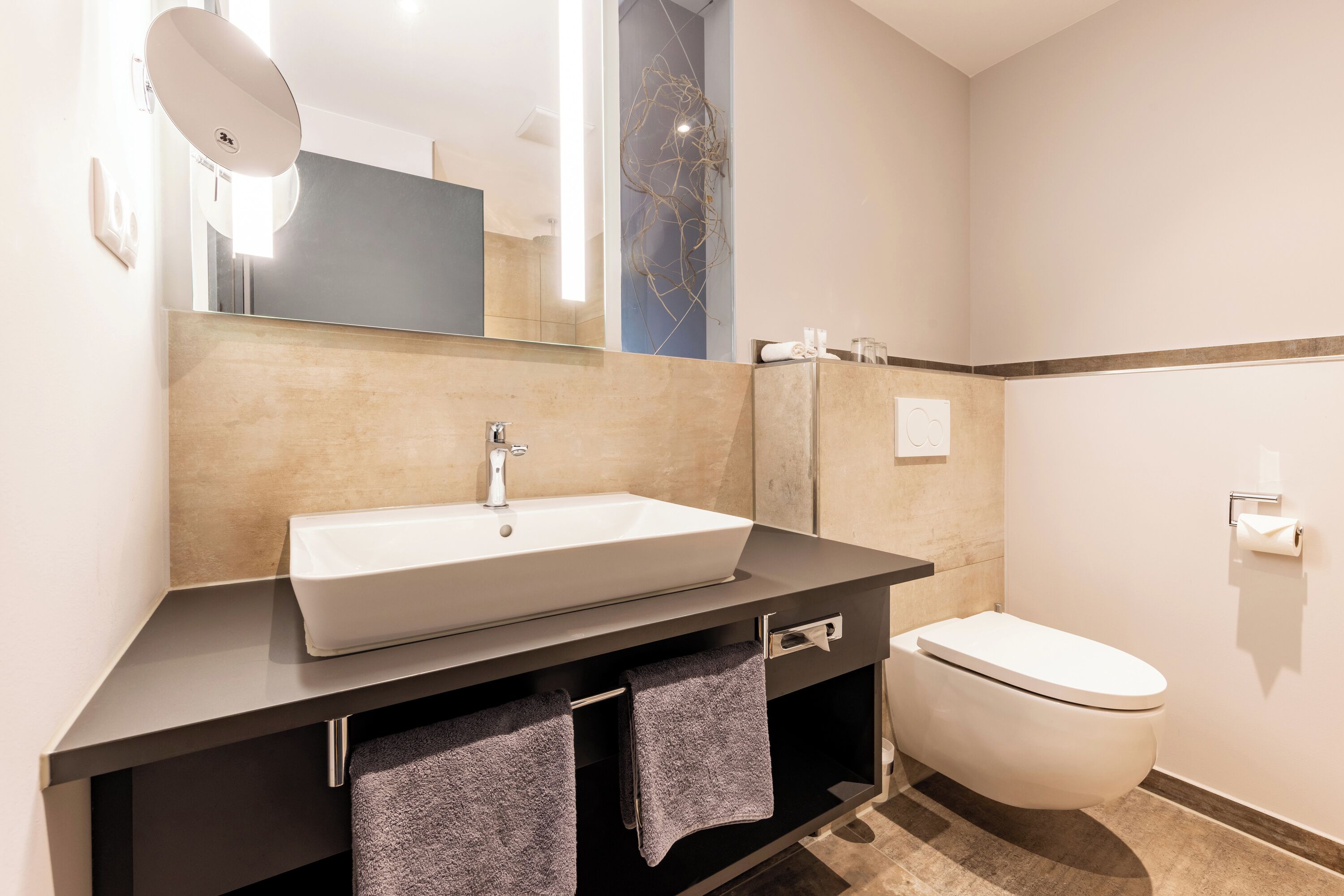 A modern bathroom with a large sink, mirror, and toilet.