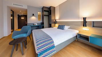 Une chambre d’hôtel moderne, dotée d’un grand lit, d’un bureau et d’une chaise.