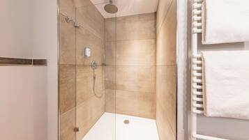 A modern shower with a glass door, a wall-mounted towel rack, and a visible shower control panel.