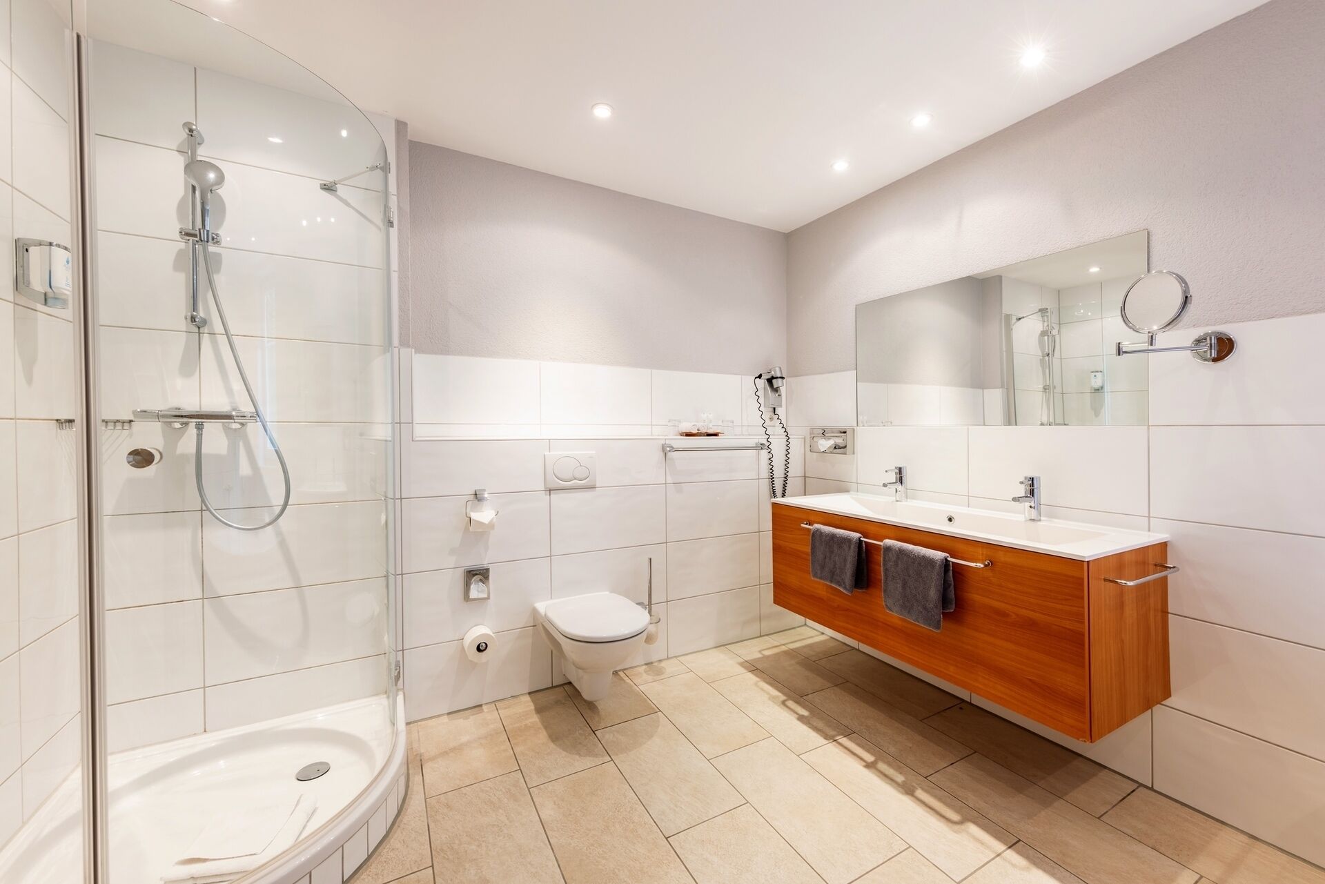 A modern bathroom with a glass-enclosed shower, a toilet, and a vanity with a mirror.