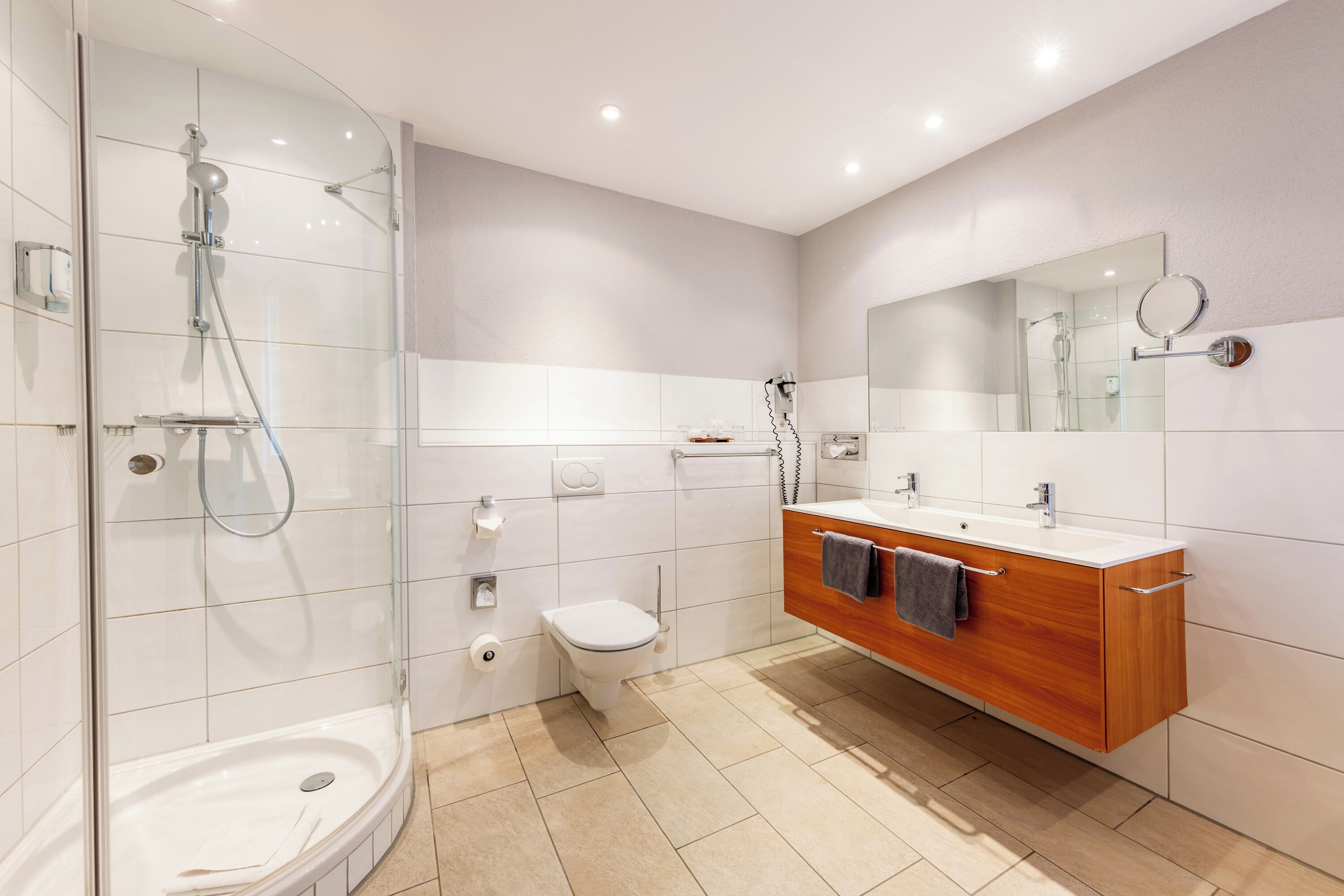 Un baño moderno con ducha envuelta en vidrio, inodoro y tocador con espejo.