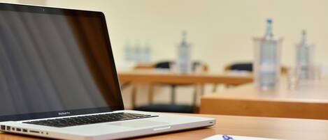 A MacBook Pro on a wooden table with a pen and paper.