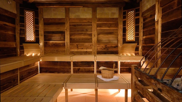 A wooden cabin interior with a bench, a table, and a bucket. - Parkhotel Maximilian Ottobeuren Resort&Spa (Ottobeuren)